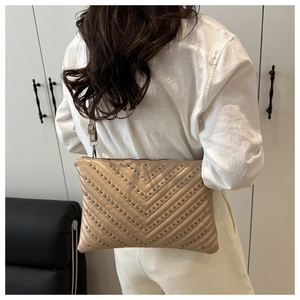 Detail of V-quilted faux leather envelope bag with silver studs and adjustable strap