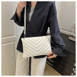 Detailed view of white envelope crossbody bag with black metal studs and V-shape quilting