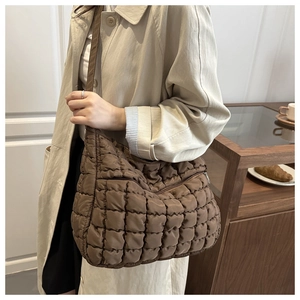 Détail du sac matelassé marron foncé porté par un mannequin dans un intérieur