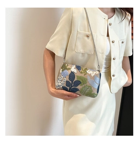 Detail of floral embroidery and sequins on a stylish crossbody bag with chain