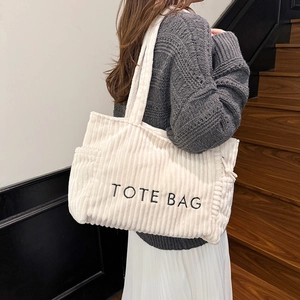 Large cream corduroy tote bag with letter print shown on shoulder for daily commute