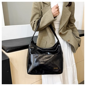 Detail of glossy black patent leather Hobo bag featuring the Fashion logo text on front