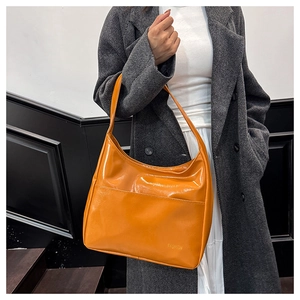 Detail of a bright orange leather tote bag with gold FASHION lettering and long strap