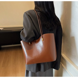 Rear view of a model wearing a large caramel patent leather tote bag for daily commute