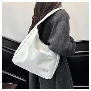 Detail of white patent leather shoulder bag with FASHION lettering on a grey wool coat