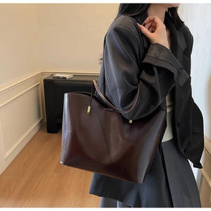 Detail view of large dark brown patent leather tote bag styled on an Asian model