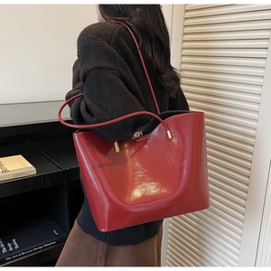 Close-up of a glossy red patent leather tote bag showing fine texture and shiny finish