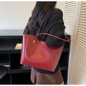 Vista trasera de un bolso tote burdeos en charol sobre modelo para referencia de talla