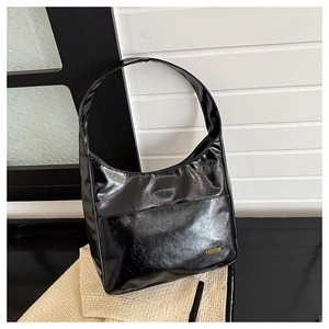 Detail of a black glossy hobo bag with a soft leather texture and golden fashion logo