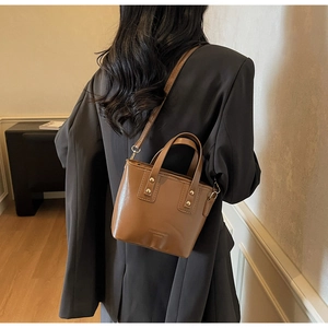 Rear view of a caramel leather tote with gold rivets on a model for size perspective