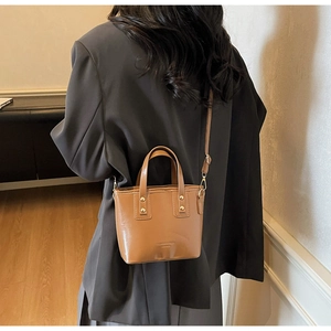 Détail du sac cabas en cuir marron brillant avec rivets dorés et logo texte mode