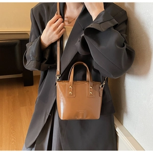 Détail du sac seau en cuir verni caramel avec rivets dorés et bandoulière amovible