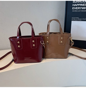 Detail of vintage bucket bags in wine red and tan with gold rivets and glossy finish