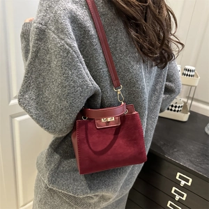 Burgundy matte crossbody bag with gold turn-lock closure shown in lifestyle setting
