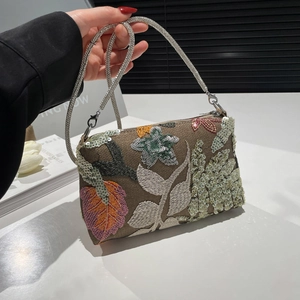 Fashionable sequin handbag with floral embroidery and rhinestone strap shown in hand