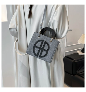 Vue détaillée du sac bandoulière en feutre gris avec logo AB noir porté par un mannequin
