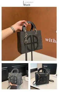 Detail view of black tote bag with gold round AB logo and adjustable strap