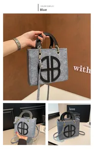 Detail of grey felt tote bag with black leather AB logo and gold metal hardware accents