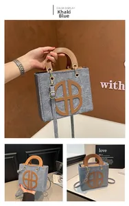 Detail of khaki blue felt tote bag with HB logo cutout and brown leather handles