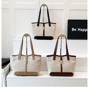 Detailed view of three large canvas tote bags with leather trim and metal buckles
