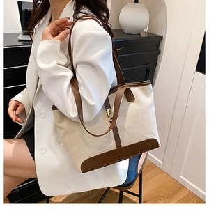 Detail of canvas tote bag with brown leather trim and golden metal clasp on a model