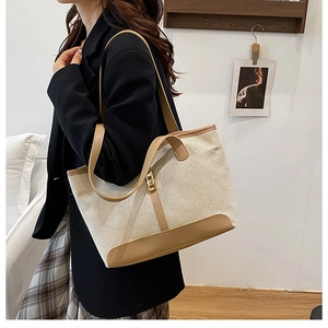 Détail du cabas en toile avec garniture en cuir marron et boucle dorée sur le mannequin