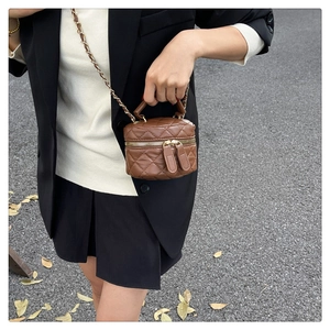Detail view of brown quilted mini bucket bag with gold chain strap on street style model