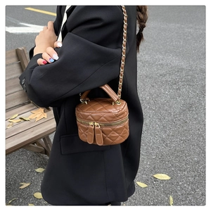 Close-up of brown quilted mini bucket bag with gold chain strap in outdoor scene