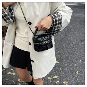 Detailed close-up of a black quilted bucket bag with gold chain and metal hardware