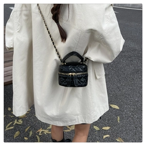 Outdoor shot showing a quilted box bag with a woven chain strap worn by a model