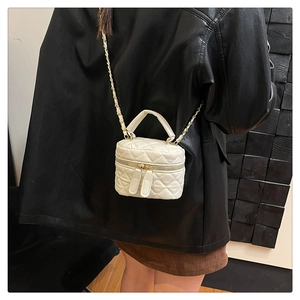 Rear view of a model wearing a mini cream quilted bucket bag with a chain strap