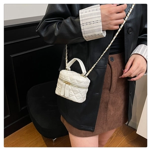 Detail of white quilted crossbody bag with dual metal zippers and leather chain strap
