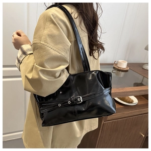 Detail of black glossy PU leather tote bag with metallic buckle strap decoration