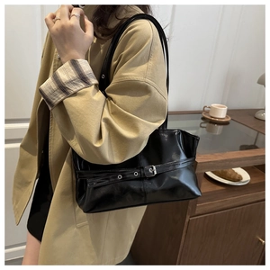 Detail of black glossy PU leather tote bag featuring a decorative belt and silver buckle
