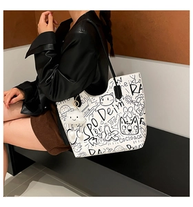 Detail of white PU tote bag featuring black graffiti print and cloud plush pendant
