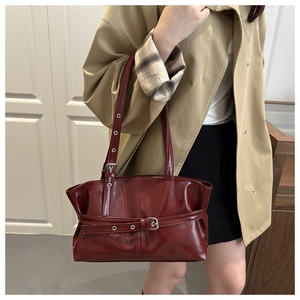 Detail of burgundy glossy faux leather tote showing metal buckle and retro texture