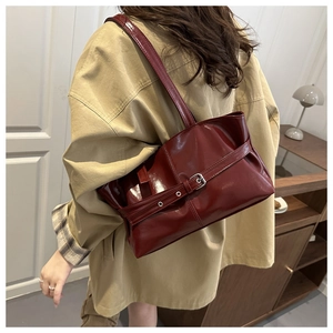 Close-up of deep red glossy PU tote bag featuring a vintage silver buckle strap detail