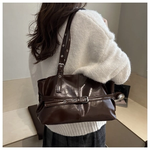 Detail of dark brown glossy tote bag featuring adjustable strap and metallic eyelets