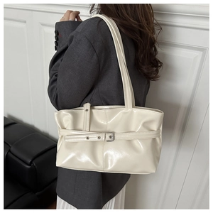 Sac à bandoulière en cuir verni crème avec boucle argentée porté par un mannequin
