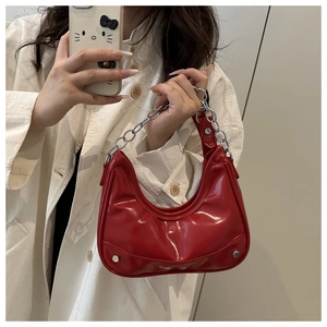 Detail of red patent leather hobo bag featuring silver rivets and chain handle detail