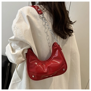 Model wearing a red croissant hobo bag with silver chain strap and rivet details