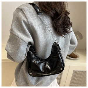 Close-up of shiny black hobo bag with silver chain and rivet details for women