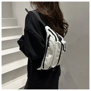 Close-up of minimalist white nylon chest bag featuring black zippers and branded label