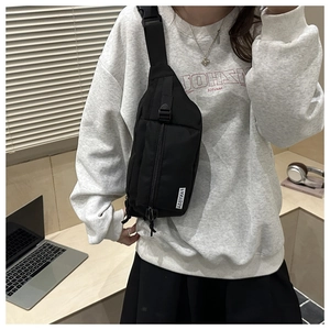 Detail of black nylon crossbody chest bag with adjustable strap and logo label