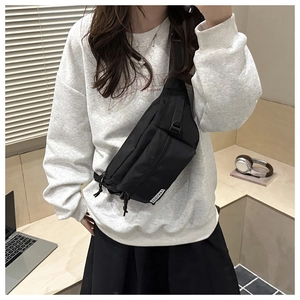 Close-up of black nylon crossbody bag with multiple zippers and adjustable strap