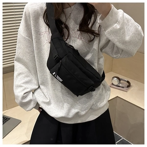 Detail of black nylon crossbody bag with dual zippers and adjustable shoulder strap