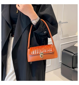 Dettaglio borsa baguette arancione con patta a coccodrillo e chiusura in oro