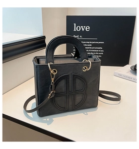 Dettaglio della borsa tote nera opaca con logo a rilievo e finiture metalliche dorate