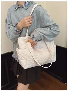 Detailed close-up of white quilted nylon tote bag with rhombus stitching and side pocket
