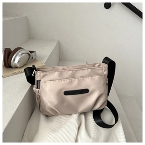 Detail of apricot nylon crossbody bag with adjustable strap and designer logo patch